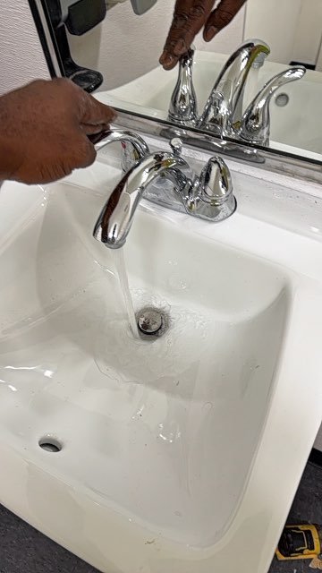 Technician adjusting a chrome faucet at a bathroom sink