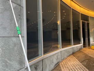 Technician cleaning commercial storefront windows with an extension pole